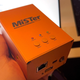 A photo of a MiSTer retro gaming box in an aluminum case being held in the author's hand.